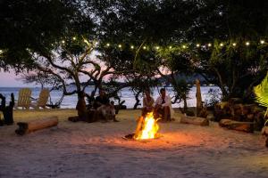 a group of people sitting around a fire on the beach at Le Pirate Gili Meno - Adults Only in Gili Meno