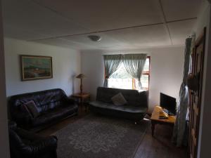 a living room with black leather furniture and a window at Misty View Farm Stay in Towerhill