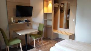 Habitación pequeña con cama, escritorio y TV. en Der Heidkrug, en Verden