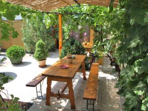 エゲルにあるCsaládi Vendégházの木製のピクニックテーブルとベンチのある庭園