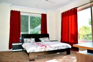 a bedroom with red curtains and a bed in front of a window at Fort and Indus River View Guest House in Skardu