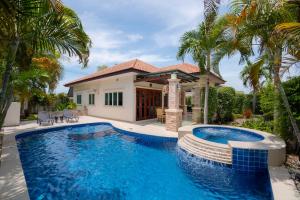 una piscina frente a una casa con palmeras en Orchid Paradise Homes OPV 30, en Hua Hin