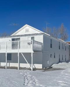 une maison blanche avec une terrasse couverte dans la neige dans l'établissement The Bodie Hotel, à Strelkovoye