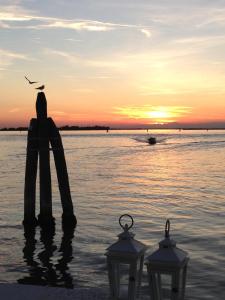 eine Person, die bei Sonnenuntergang im Wasser steht in der Unterkunft Antica Dogana in Cavallino-Treporti