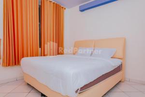 a bed in a room with an orange curtain at Ungu Kangen Hotel Bogor Mitra RedDoorz in Bogor