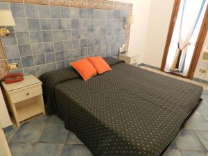 a small bedroom with a black bed with orange pillows at Hotel Punta Mesco in Monterosso al Mare