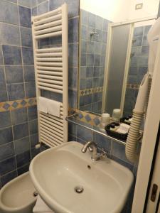 モンテロッソ・アル・マーレにあるホテル プンタ メスコの青いタイル張りのバスルーム(シンク、鏡付)