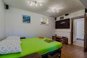 a bedroom with a green bed and a flat screen tv at Apartments Mir - perfect location & cosy in Korčula