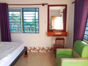 a bedroom with a bed and a mirror and a chair at Silver Dolphin Guesthouse & Restaurant in Kratie