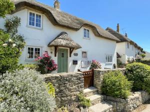 a cottage with a thatched roof at Cajun Cottage in Wareham