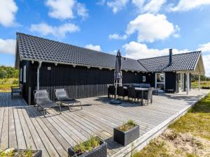 eine Holzterrasse mit Stühlen und einem Sonnenschirm auf einem Haus in der Unterkunft Holiday home Fanø XLIII in Fanø