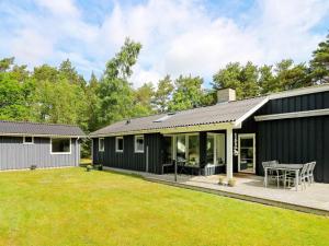 una casa con un exterior negro y un patio en Holiday Home Jægerparken en Odde