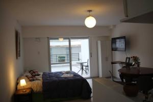 Un dormitorio con una cama y una mesa y un balcón. en Apart con Patio Exclusivo - Rosario Centro - Excelente - Cochera Opcional, en Rosario