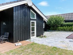 una casa negra con una silla en una terraza de madera en 10 person holiday home in Hadsund, en Hadsund