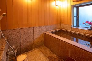 baño con bañera, aseo y ventana en Tabist Ooriya Kochi, en Sagamichō