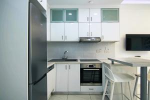 a kitchen with white cabinets and a stainless steel refrigerator at Phaedrus Living: Seaside Luxury Flat Lighthouse 66 in Paphos