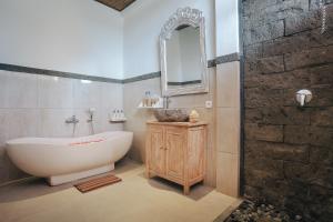 ein Badezimmer mit einer weißen Badewanne und einem Spiegel in der Unterkunft Sitala Suite in Ubud