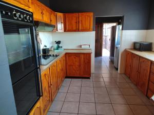 uma cozinha com armários de madeira e um frigorífico preto em Boh- House em Graskop