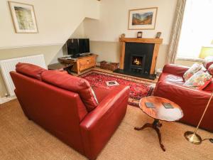 sala de estar con 2 sofás de cuero rojo y chimenea en Tiplady Cottage, en Leyburn