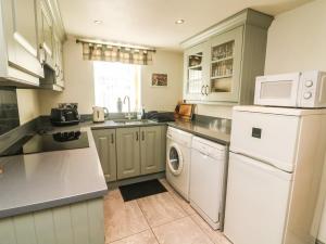 a kitchen with a white refrigerator and a dishwasher at Tiplady Cottage in Leyburn