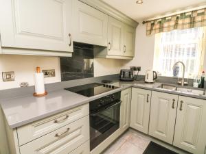 a kitchen with white cabinets and a stove top oven at Tiplady Cottage in Leyburn +23 photos