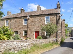 an old stone house with a red door at Tiplady Cottage in Leyburn