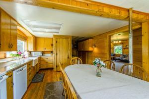 a kitchen with wooden walls and a table with flowers on it at McKinnon's Beach House in Rockaway Beach