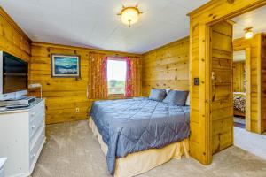 a log cabin bedroom with a bed and a tv at McKinnon's Beach House in Rockaway Beach