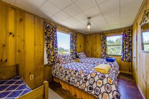 a bed in a room with wooden walls and windows at McKinnon's Beach House in Rockaway Beach