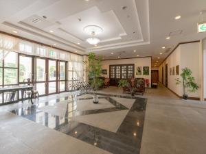 a large lobby with a table and chairs and windows at Ada Garden Hotel Okinawa in Kunigami