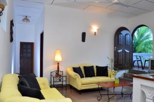 ネゴンボにあるアーユーボーワン ゲストハウスのリビングルーム(黄色のソファ2台、テーブル付)