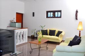 a living room with two couches and a tv at Ayubowan Guesthouse in Negombo