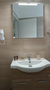 bagno con lavandino bianco e specchio di Frygano Apartments 1 a Oitylo