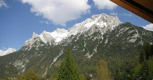 vistas a una montaña nevada con un árbol en Gästehaus Kurparkfrieden, en Mittenwald