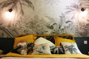 uma cama com almofadas e um papel de parede com palmeiras em Le Petit Bégou em Saint-Auban-dʼOze