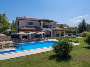 a large house with a swimming pool in front of it at Picturesque Villa in Verteneglio with Pool in Brtonigla