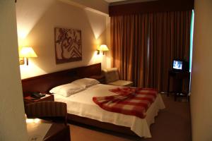 um quarto de hotel com uma cama com um cobertor vermelho em Hotel de Arganil em Arganil