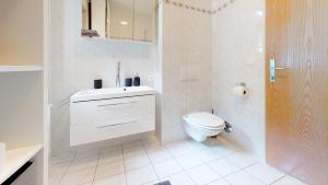 a white bathroom with a toilet and a sink at Ferienwohnung Kathrin in Huben