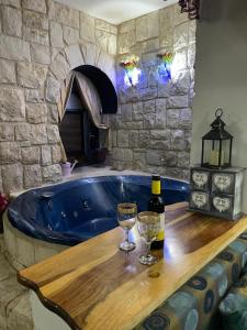 a bath tub with a bottle of wine and two glasses at צימר מאיה in Ani'am
