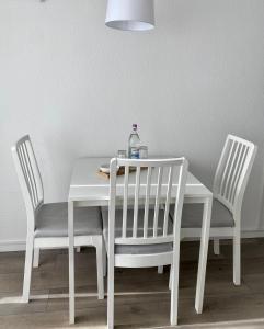 a white table with two chairs and a bottle on it at Seeblickapp. „Eure Auszeit“ in Goslar