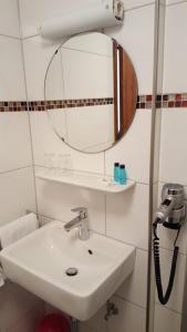 ein Bad mit einem Waschbecken und einem Spiegel in der Unterkunft Landgasthof Groh in Ulrichstein
