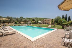 une grande piscine avec des chaises et une maison dans l'établissement Poggio Primo - Bilocale Brando, à Castiglion Fibocchi