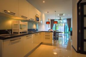 a kitchen with white cabinets and a sink and a table at Two Bedroom Onyx Villa Nai Harn in Nai Harn Beach