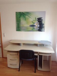 a desk with a chair and a painting on the wall at Ruhige Wohnung in Schnaitheim bei Heidenheim in Heidenheim