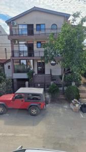 un camión rojo estacionado frente a una casa en VILA LITORIA, en Costinesti