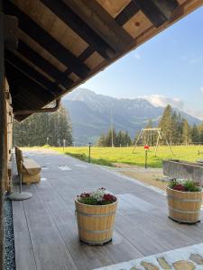 um alpendre com dois vasos de plantas e um parque infantil em Chalet Schwendli em Schwarzsee