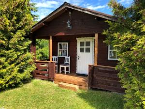 eine kleine Holzhütte mit einer Veranda und einer weißen Tür in der Unterkunft Merejussi Puhkemajad in Pärna