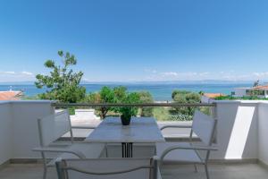 een tafel en stoelen op een balkon met uitzicht op de oceaan bij Summer Feelings in Skala Sotiros