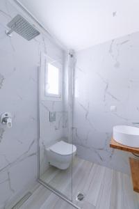 a white bathroom with a toilet and a sink at Summer Feelings in Skala Sotiros