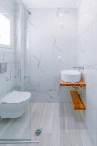a white bathroom with a toilet and a sink at Summer Feelings in Skala Sotiros